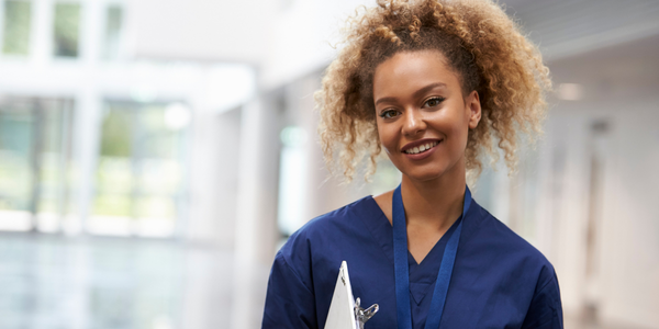 black nurse smiling and holding a clipboard
